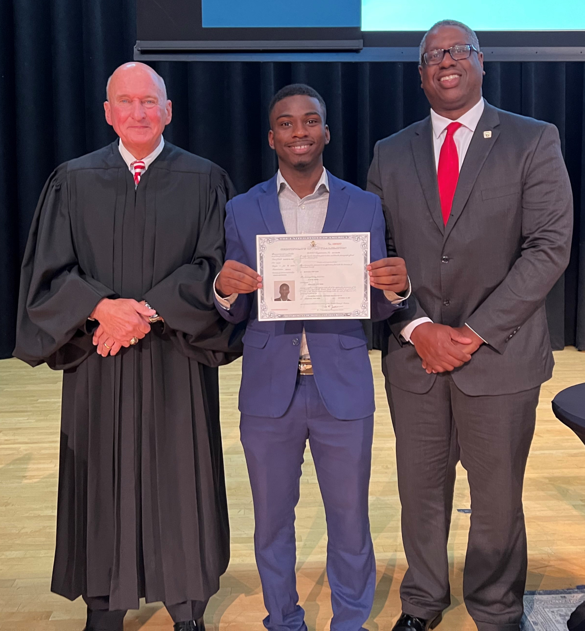 New American citizen and OCC student Juhudi Boazi (center) is pictured with Honorable Magistrate Judge David E. Peebles (left) and OCC President Dr. Warren Hilton (right).
