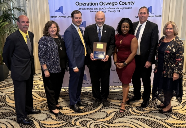 Pictured with the ALLY AWARD are (left to right): John Halleron and Kellie Greene of the SBDC, Austin Wheelock of Operation Oswego County, Bob Griffin and Sonya Smith of the SBDC, Mark Manning of Onondaga Community College, and Ellen Holst of Operation Oswego County.