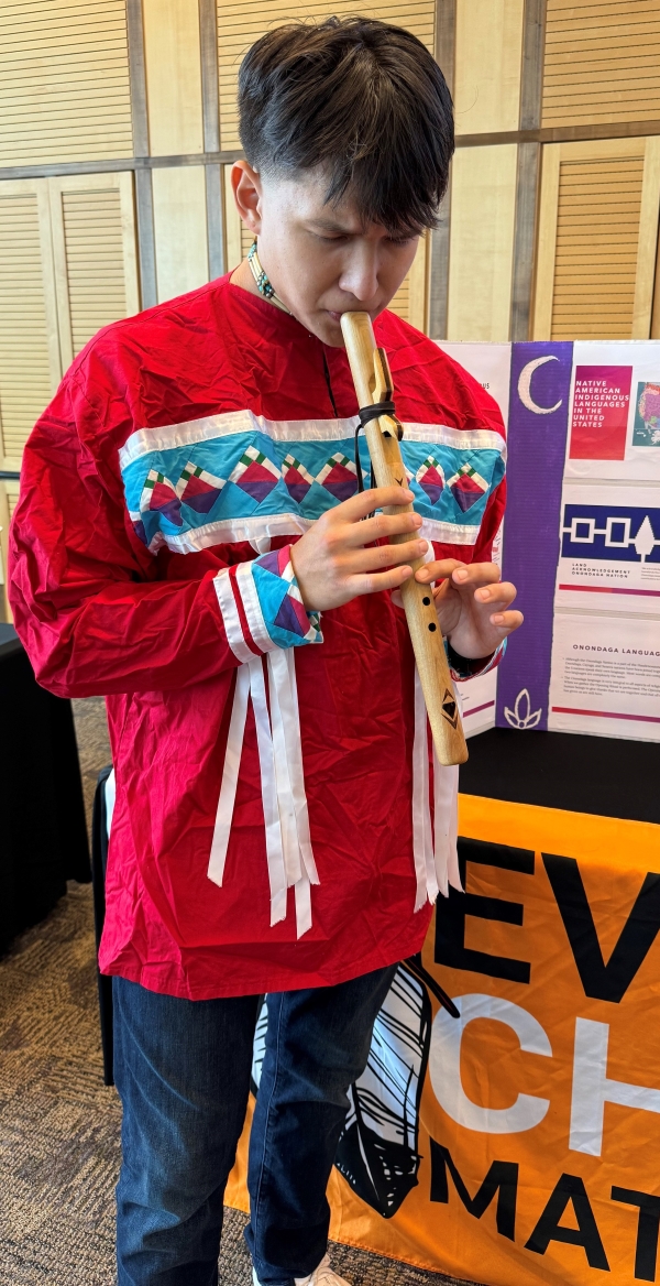 Kocechvmpv Emarahle plays the flute at Tuscarora Language table.