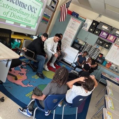 Members of Onondaga Community College's Extraordinary Men of Distinction speak with students at Syracuse's Meachem Elementary School.