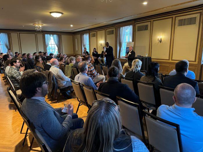 OCC President Warren Hilton (standing) speaks at the beginning of the Topics on Tap networking and panel discussion. Seated behind him (left to right) are Andrew Schuster, Lauren Staniec, Andy Breuer, and Glenn LaPoint '16. OCC President Warren Hilton (standing) speaks at the beginning of the Topics on Tap networking and panel discussion. Seated behind him (left to right) are Andrew Schuster, Lauren Staniec, Andy Breuer, and Glenn LaPoint '16.